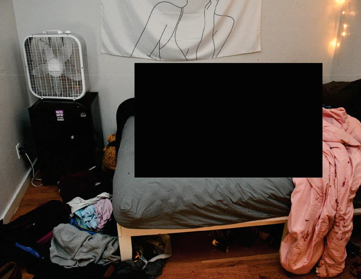 Bed with gray sheet and pink blanket beside a box fan, with much of the bed redacted.