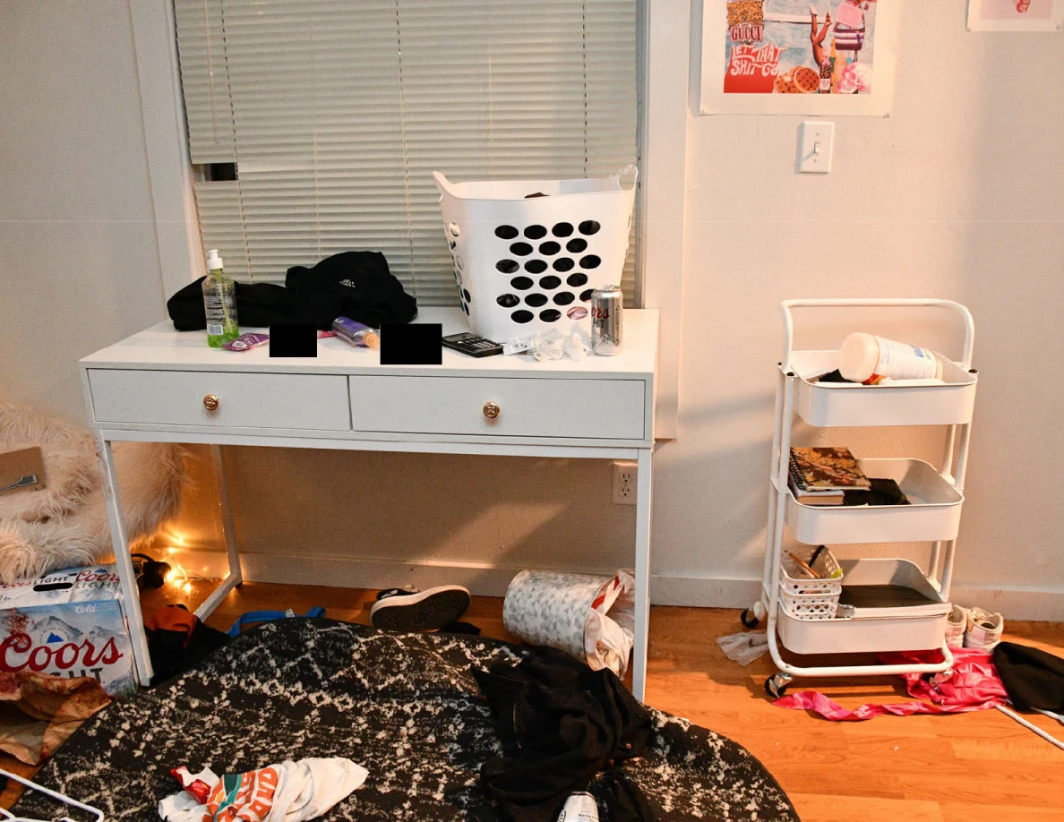 White desk with laundry basket and bottles beside a rolling cart and patterned round rug.