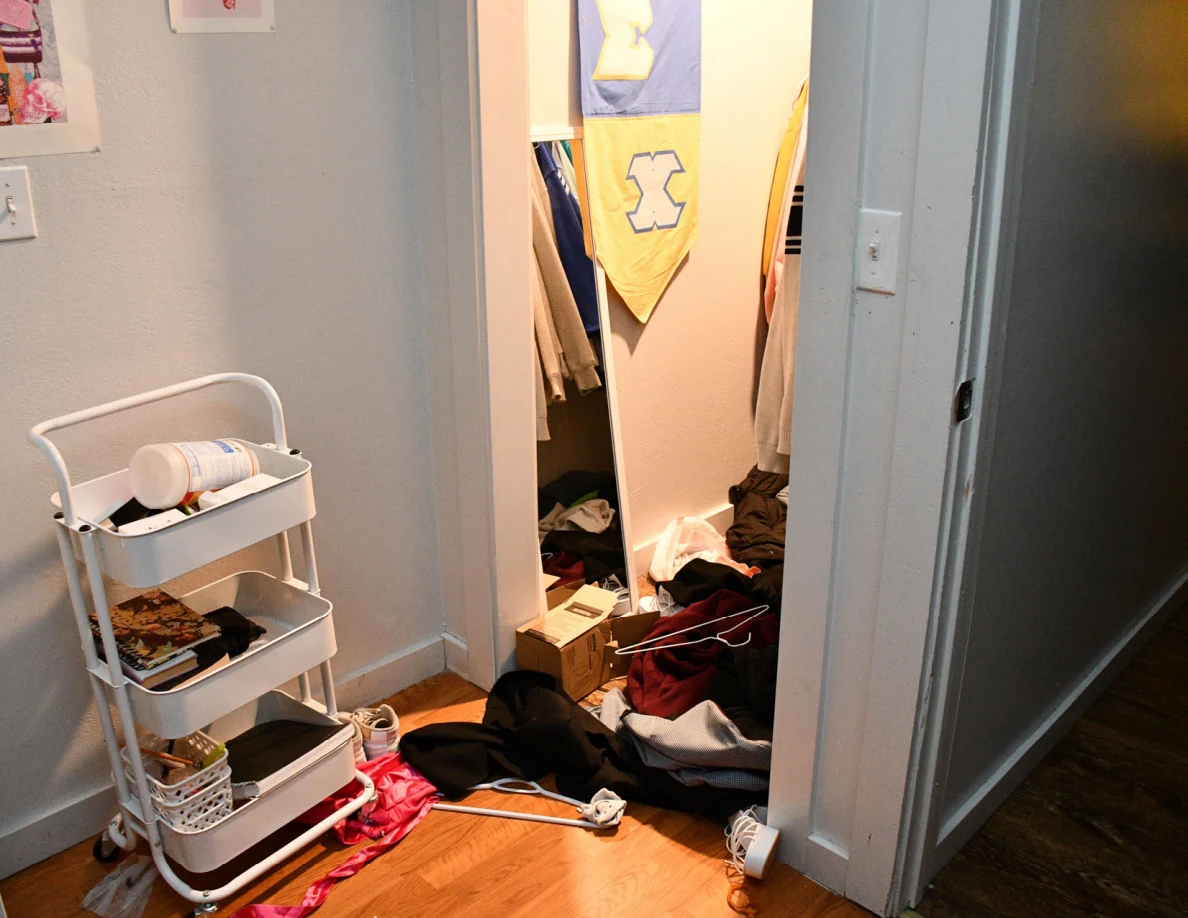 Rolling cart beside an open closet with a blue-and-yellow banner and scattered clothing.