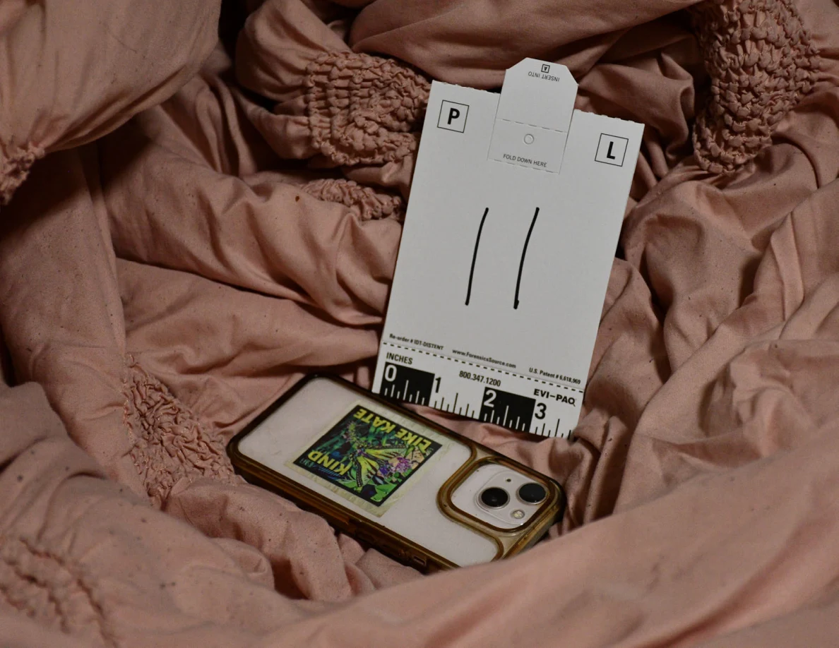 Phone on pink bedding beside scale card 11.