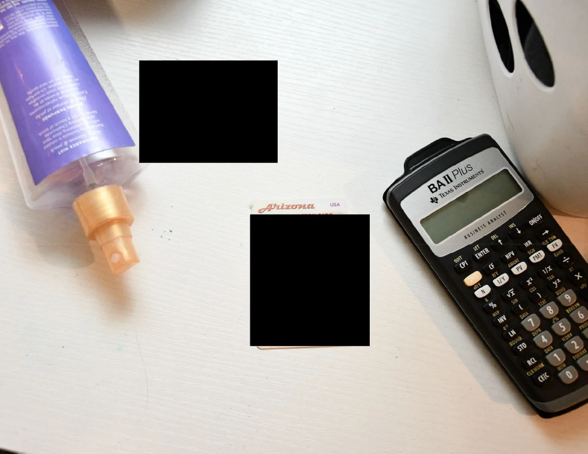 Calculator beside a redacted Arizona identification card and purple spray bottle.