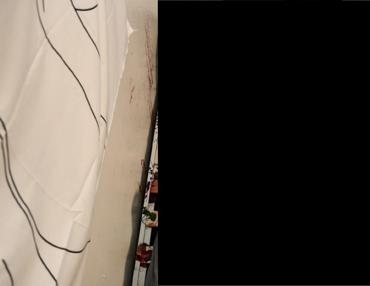Wall hanging beside reddish wall marks, with most of the image obscured by a redaction.