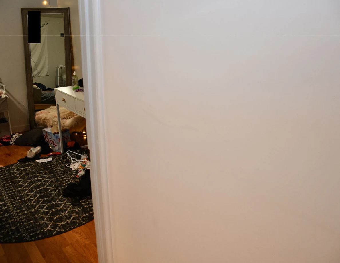 Plain wall near a bedroom doorway with a faint curved surface mark.