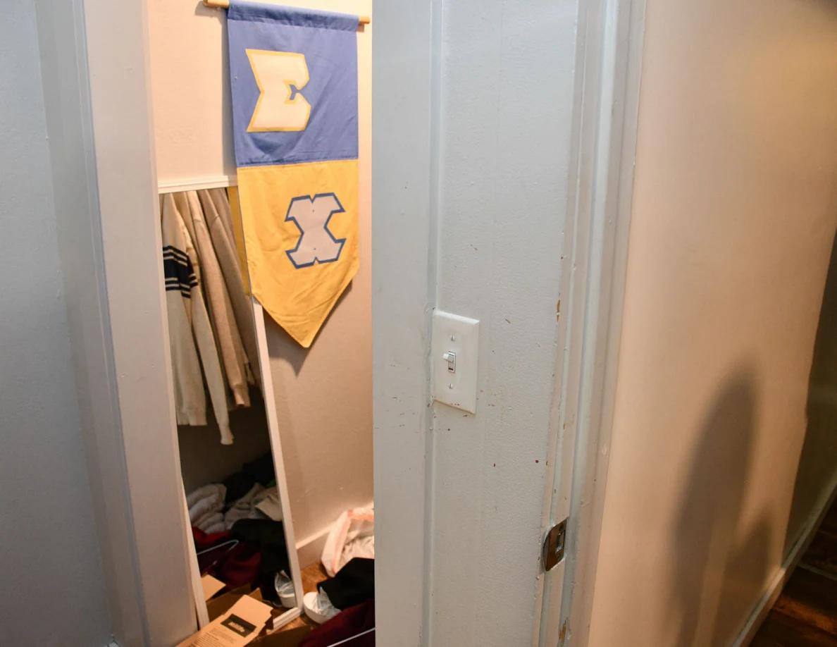Open closet with blue-and-yellow banner beside a wall light switch and marked trim.