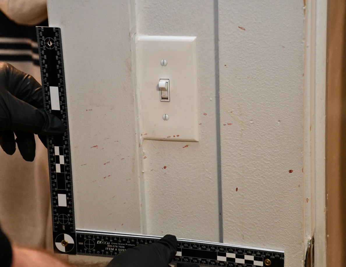L-shaped measuring scale around a light switch and reddish marks on pale paint.