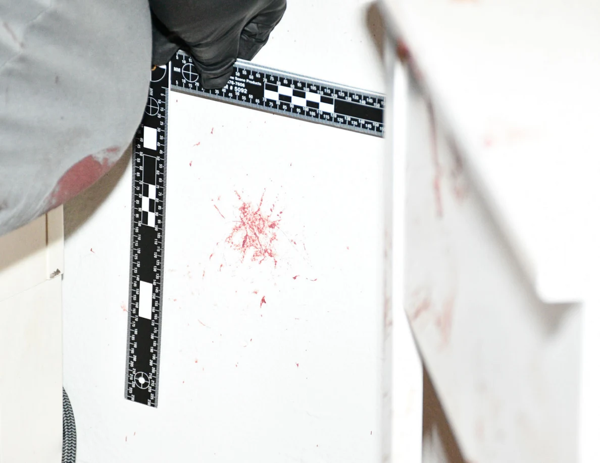 L-shaped measuring scale surrounding a reddish mark on the wall beside furniture.