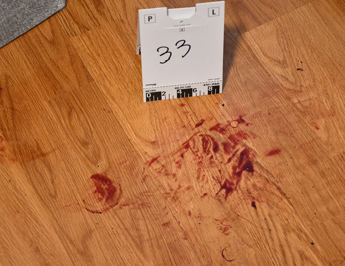 Scale card 33 beside reddish marks on wood-pattern flooring.