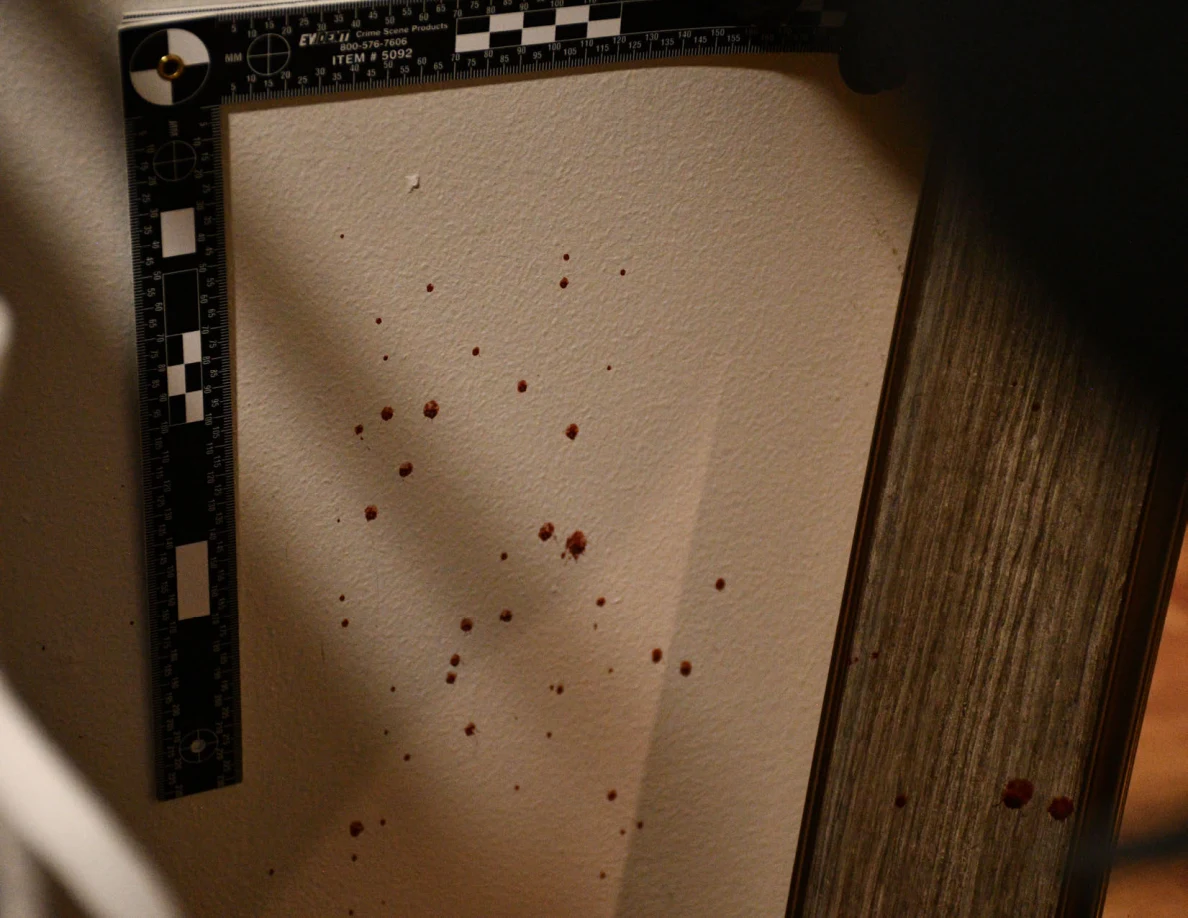 L-shaped measuring scale around reddish wall spots beside a mirror.