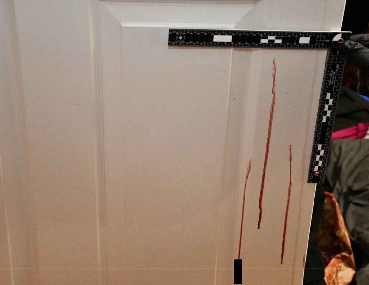 L-shaped measuring scale around vertical reddish door streaks.