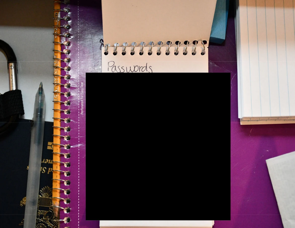 Close view of a spiral pad with blacked-out contents on a purple notebook.