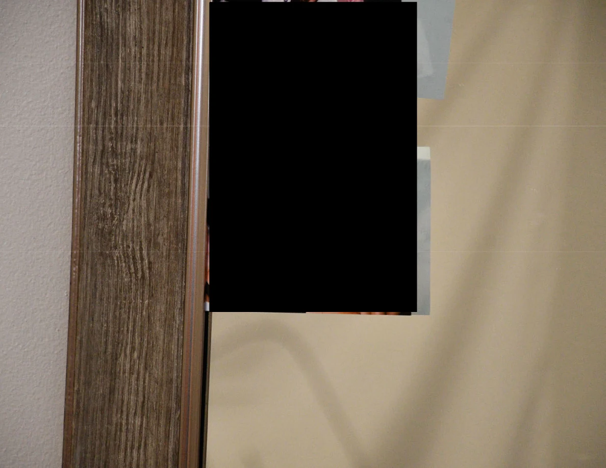 Close view of a wood-look mirror frame beside a blacked-out area.