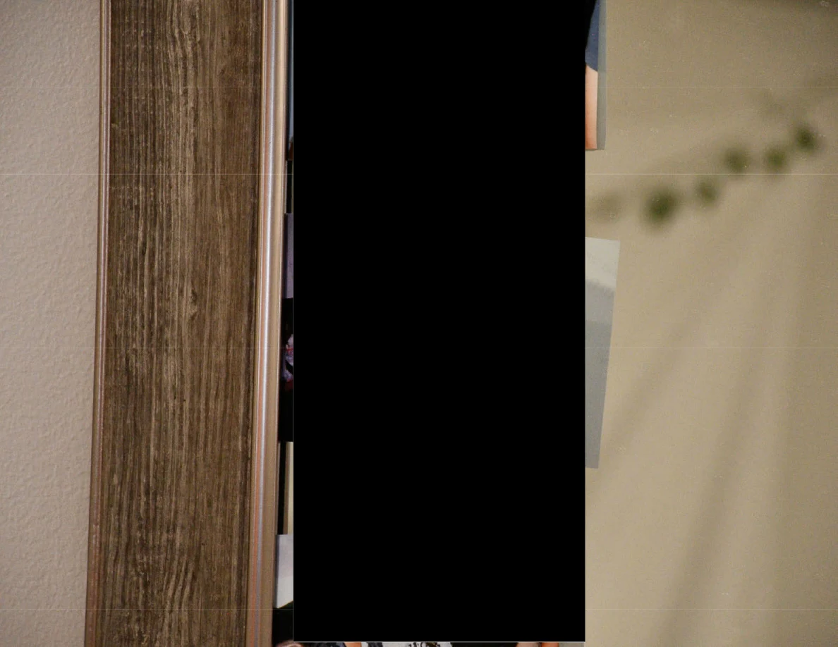 Close view of a mirror edge beside a tall black redaction.