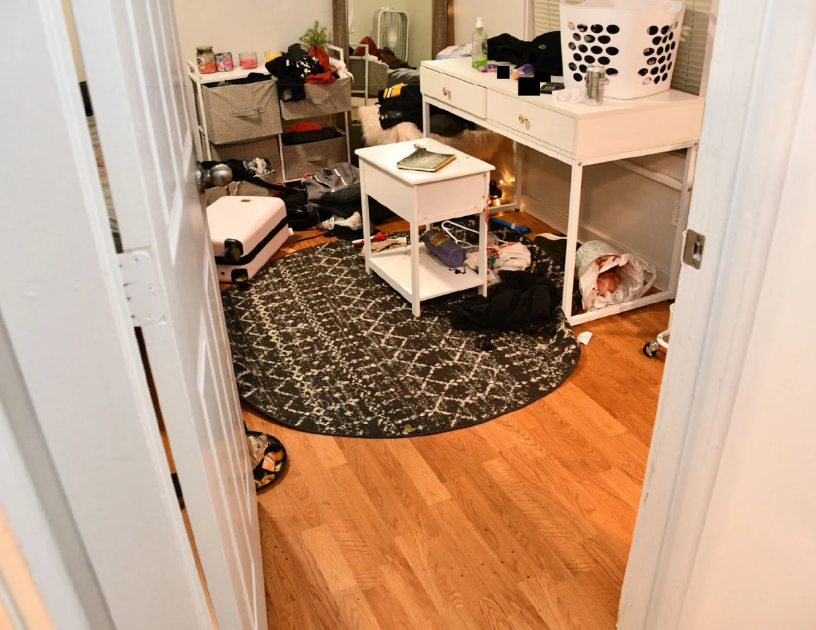 White desk and small side table above a patterned round rug, with clothing and a laundry basket.