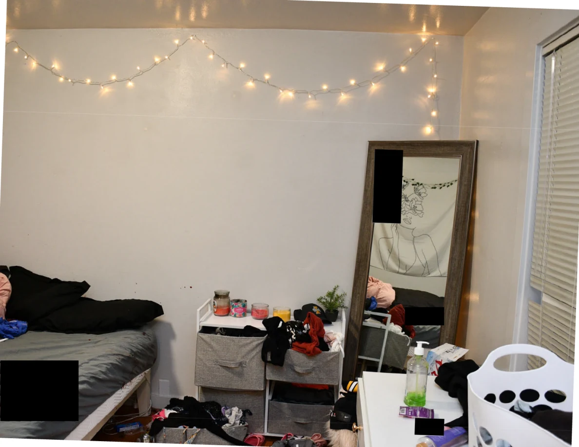 Bedroom wall with string lights above a tall mirror and fabric drawers beside a white desk.