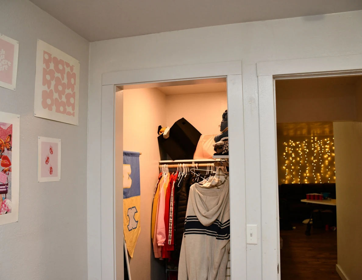 Upper view of an open clothes closet and bedroom doorway with small wall pictures.