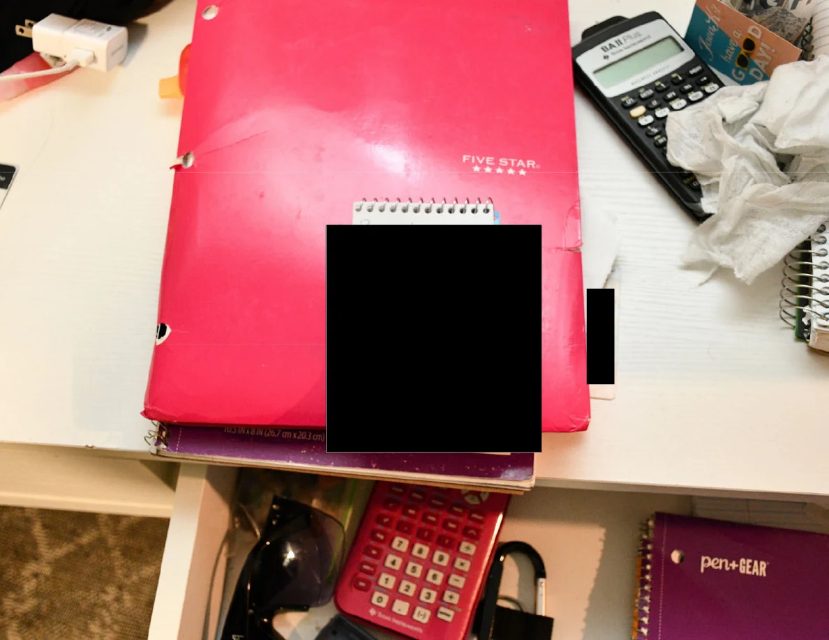 Pink notebook, calculators and tissues with a small spiral pad whose contents are blacked out.