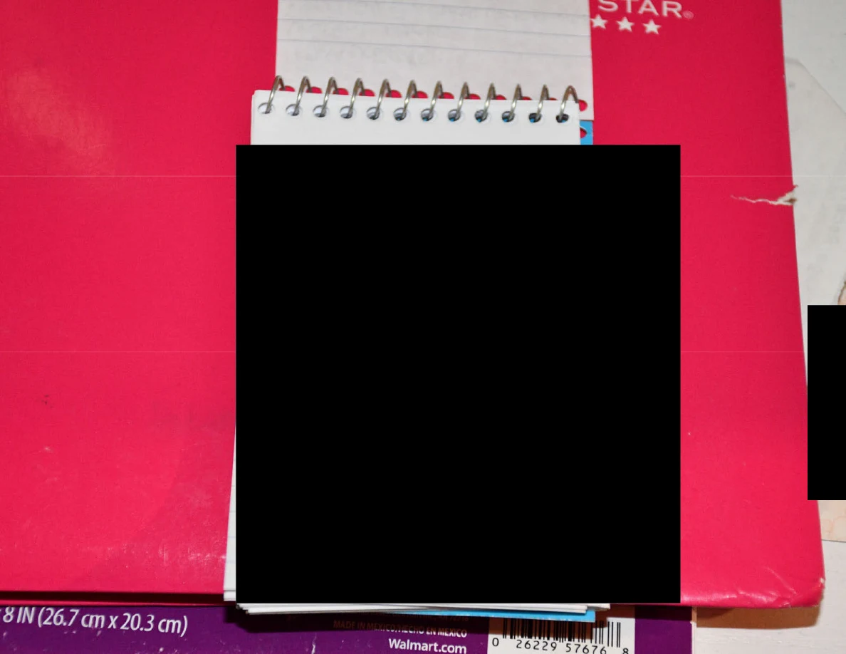 Small spiral pad with its contents blacked out on a pink notebook.