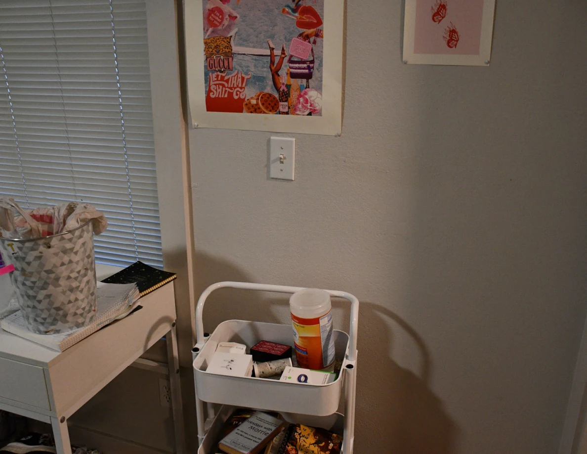 White rolling storage cart with a wipes canister beside a desk and patterned basket.