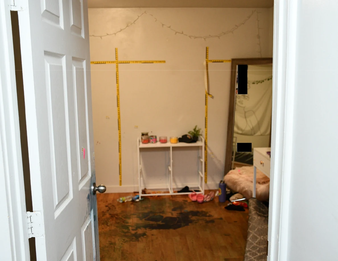 Bedroom wall with yellow measuring scales above a white cabinet and dark reddish floor marks.