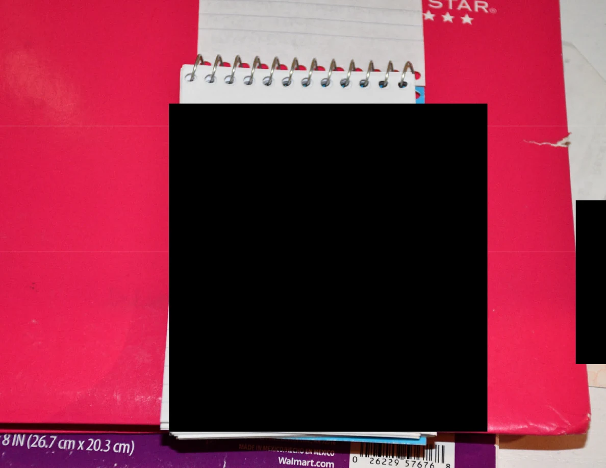 Close view of blacked-out spiral-pad contents on a pink notebook.
