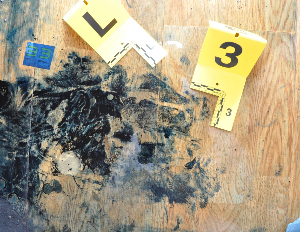 Close view of dark floor marks beside yellow markers L and 3 and a blue scale card.