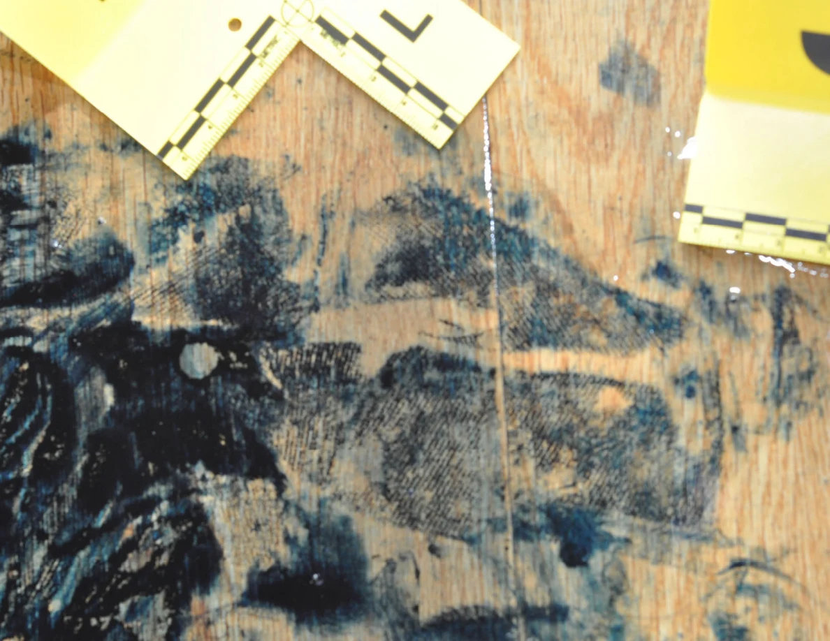 Close view of dark marks and a pale seam on flooring between yellow scale cards.