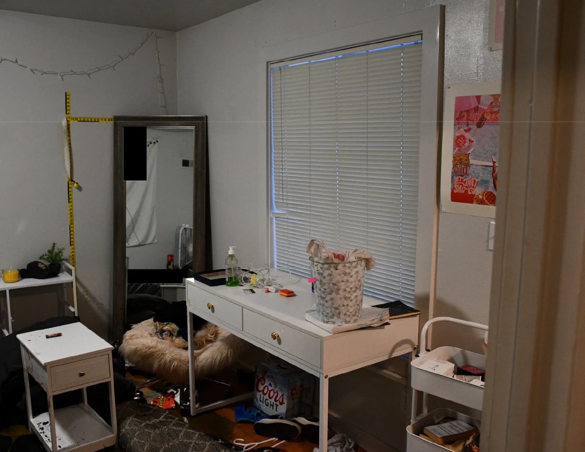 Bedroom desk and basket beside closed blinds, a tall mirror and wall scales.