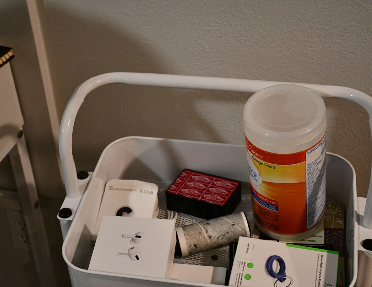 White cart shelf holding wipes, earbud packaging, small boxes and lint rollers.