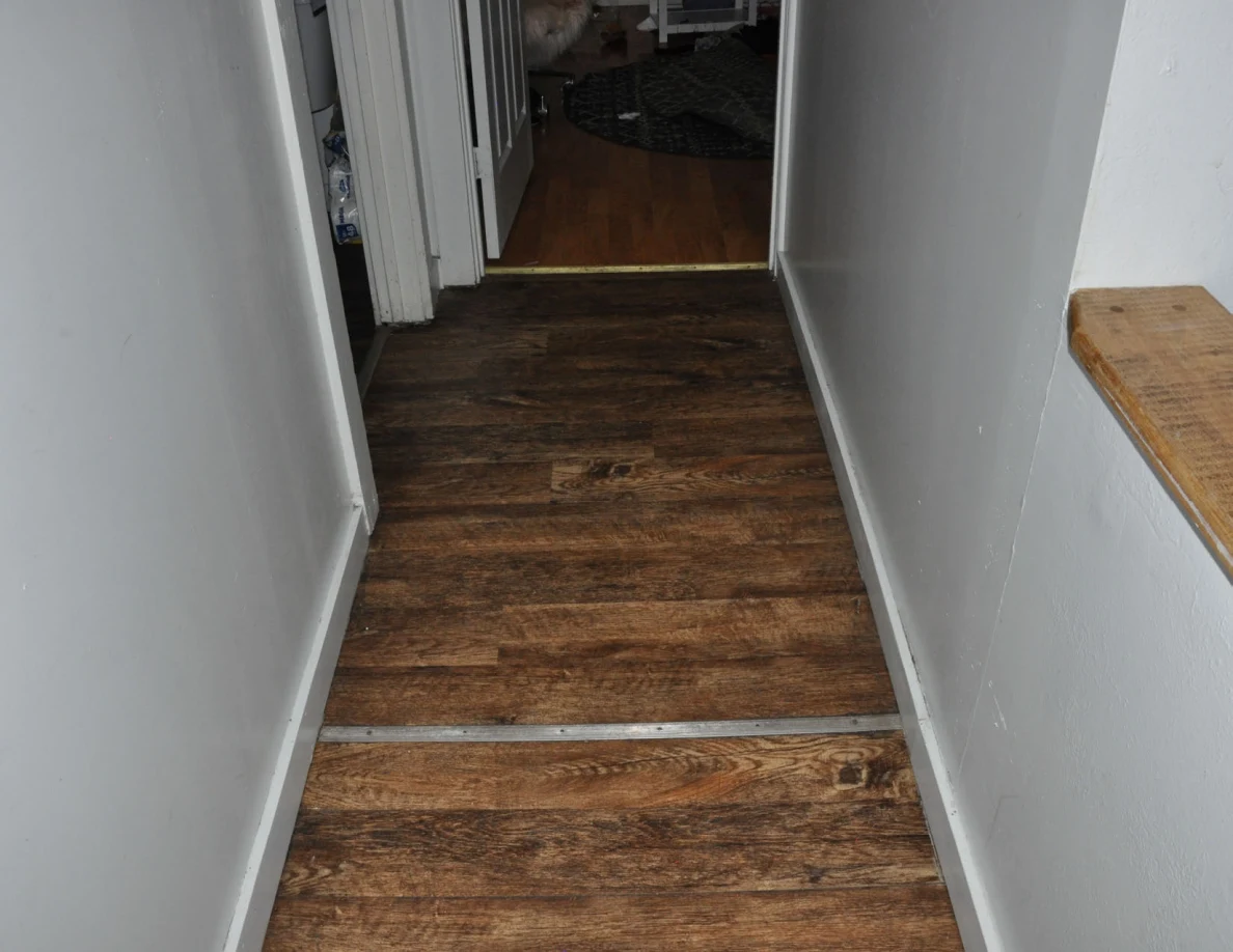 Hallway flooring leading to an open bedroom doorway.