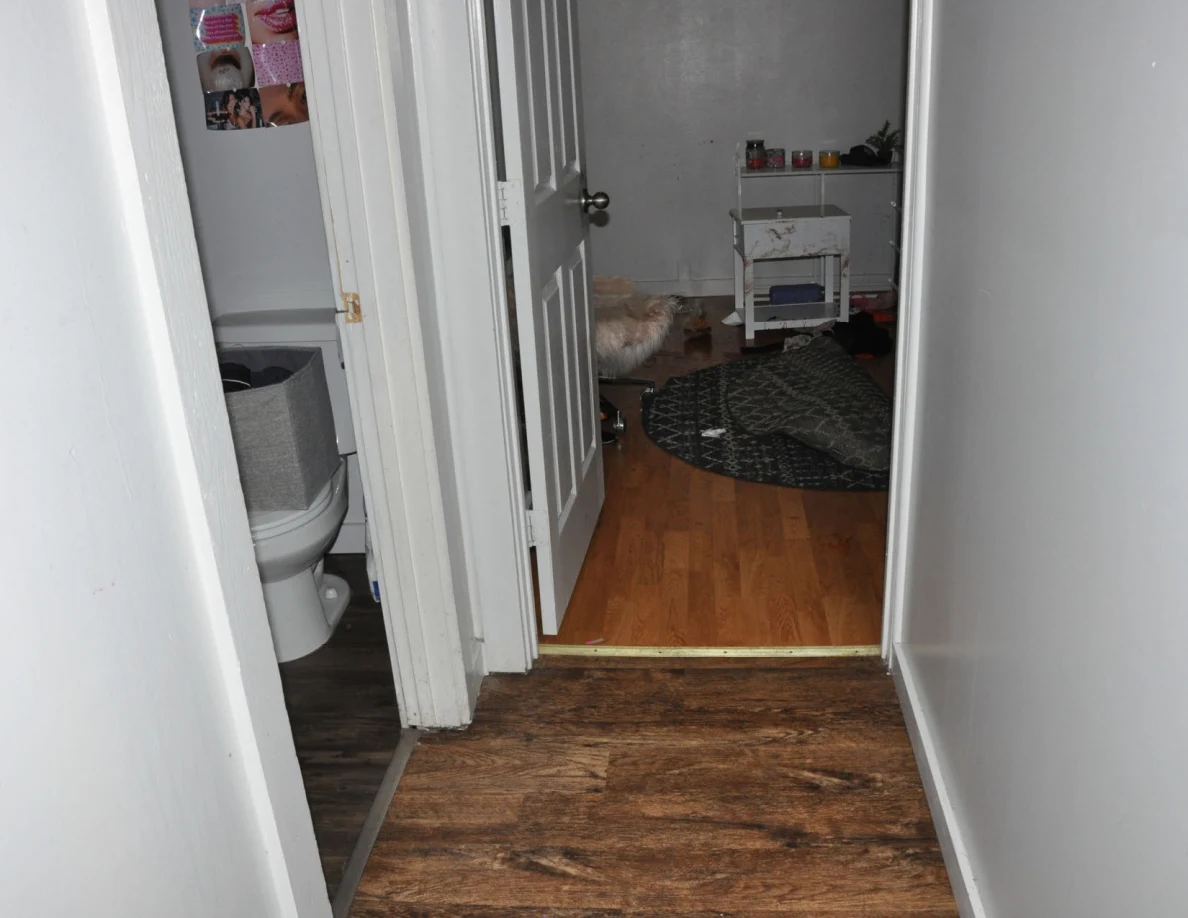 Hallway beside an open bathroom with a visible toilet and bedroom doorway.
