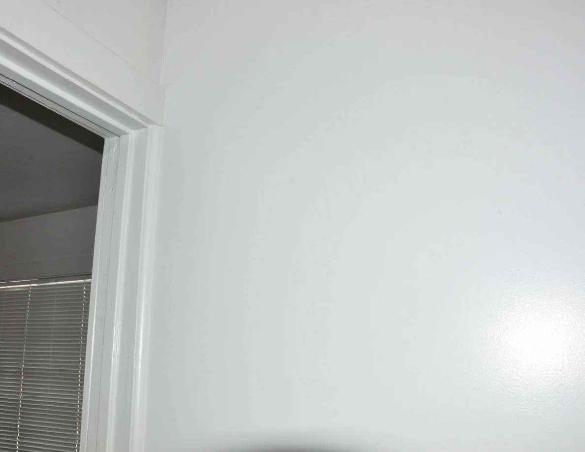 Upper white wall and door frame beside a bedroom entrance.