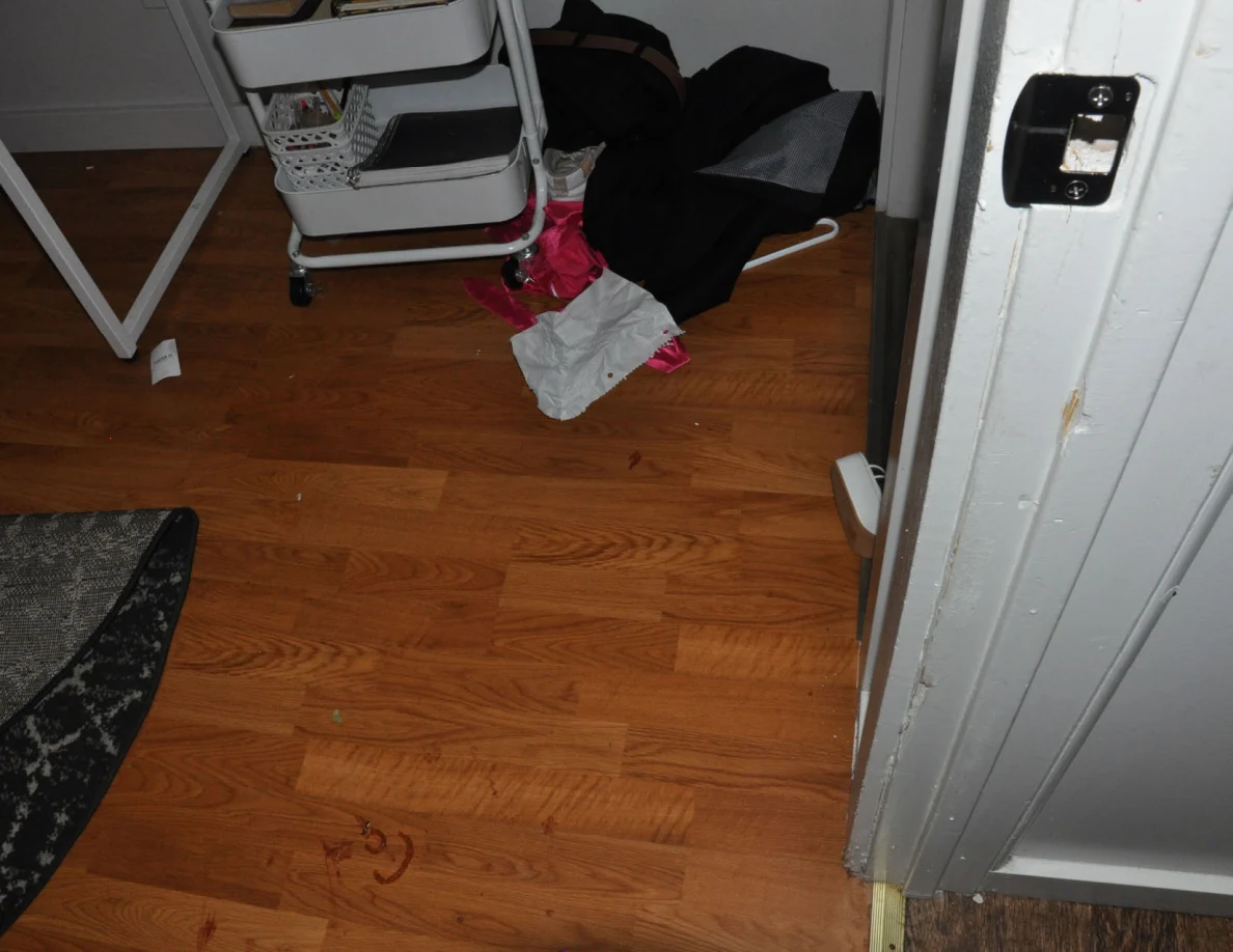 Doorway floor beside scattered clothing, a rolling cart and latch plate.