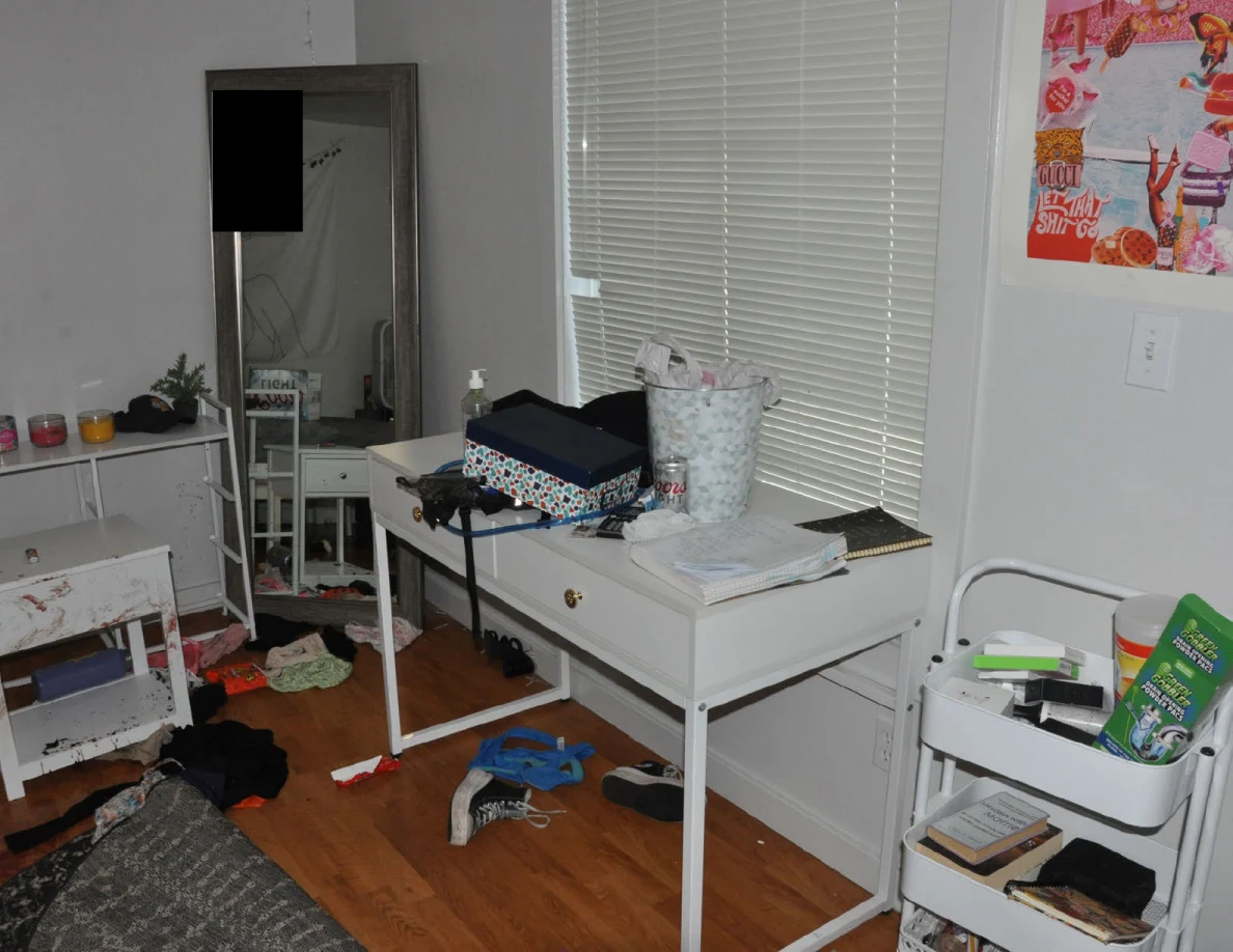 White desk with a basket and boxes beside a mirror and scattered floor items.