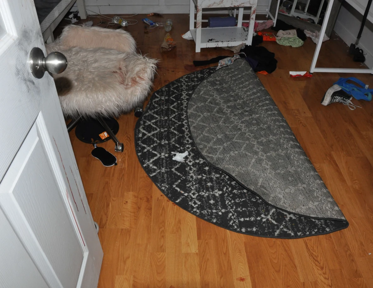 Folded circular patterned rug beside a fluffy chair and white furniture.