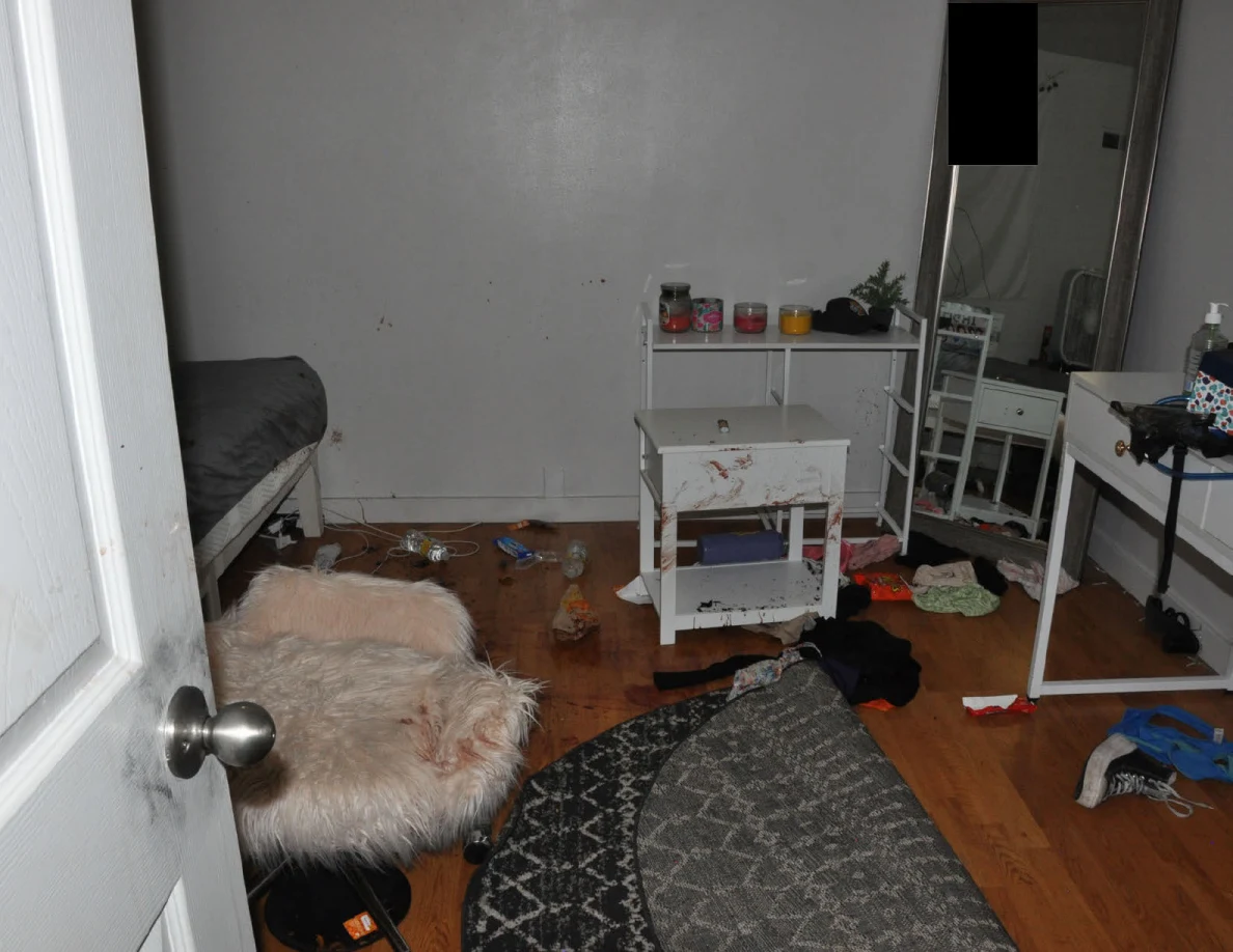 Bedroom doorway view with a fluffy chair, folded rug, mirror and white furniture.