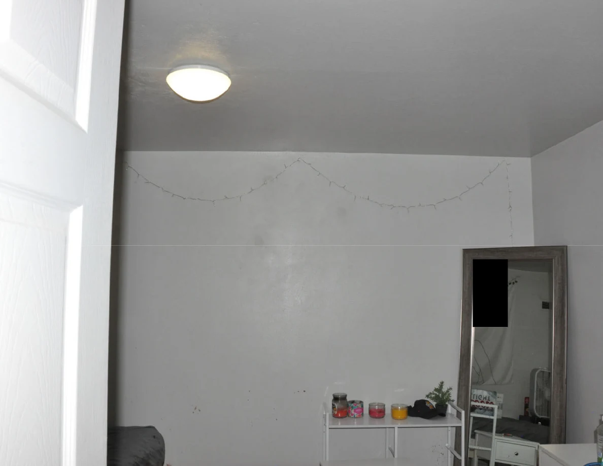 Bedroom ceiling light and string lights above a mirror and small cabinet.