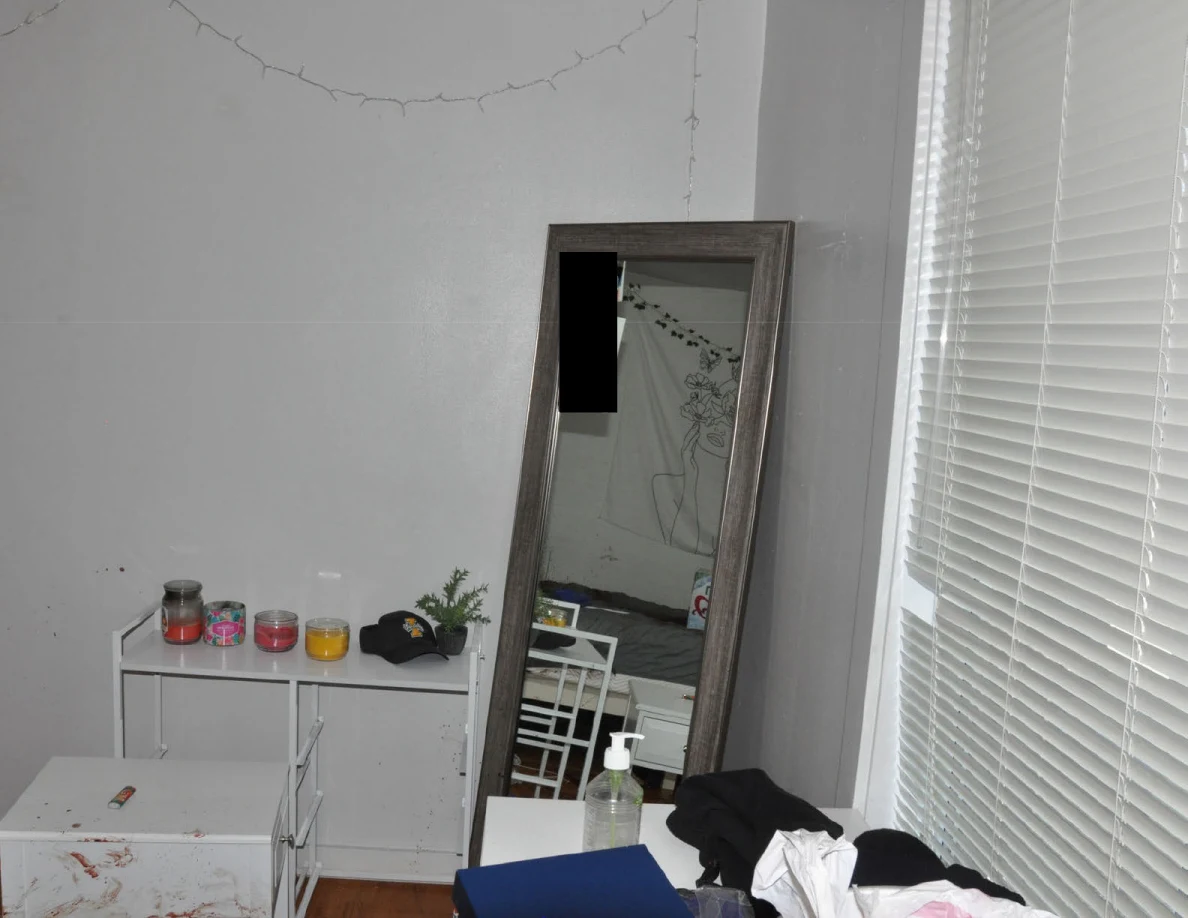 Tall framed mirror and white cabinet below string lights beside closed blinds.