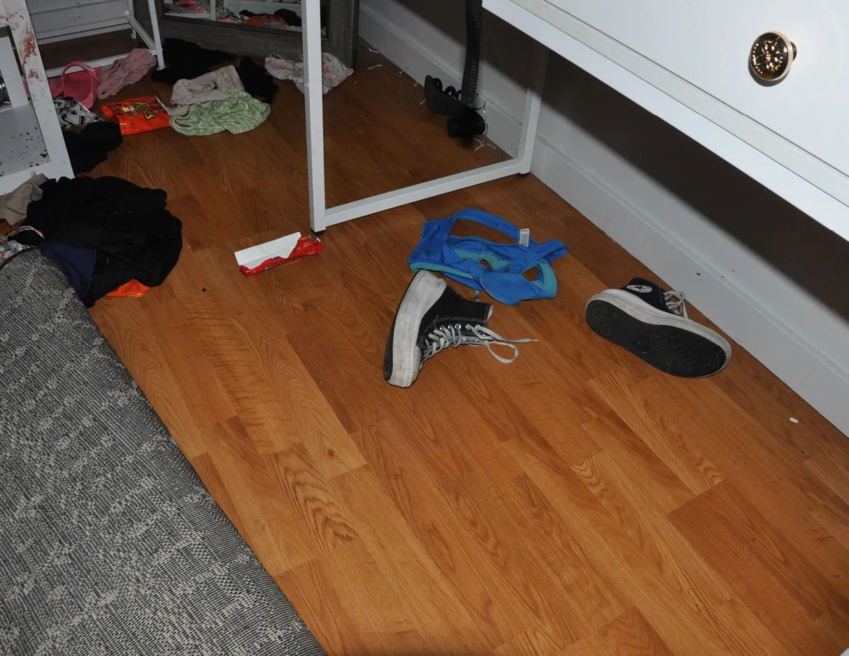 Scattered sneakers and blue fabric beneath a white desk.