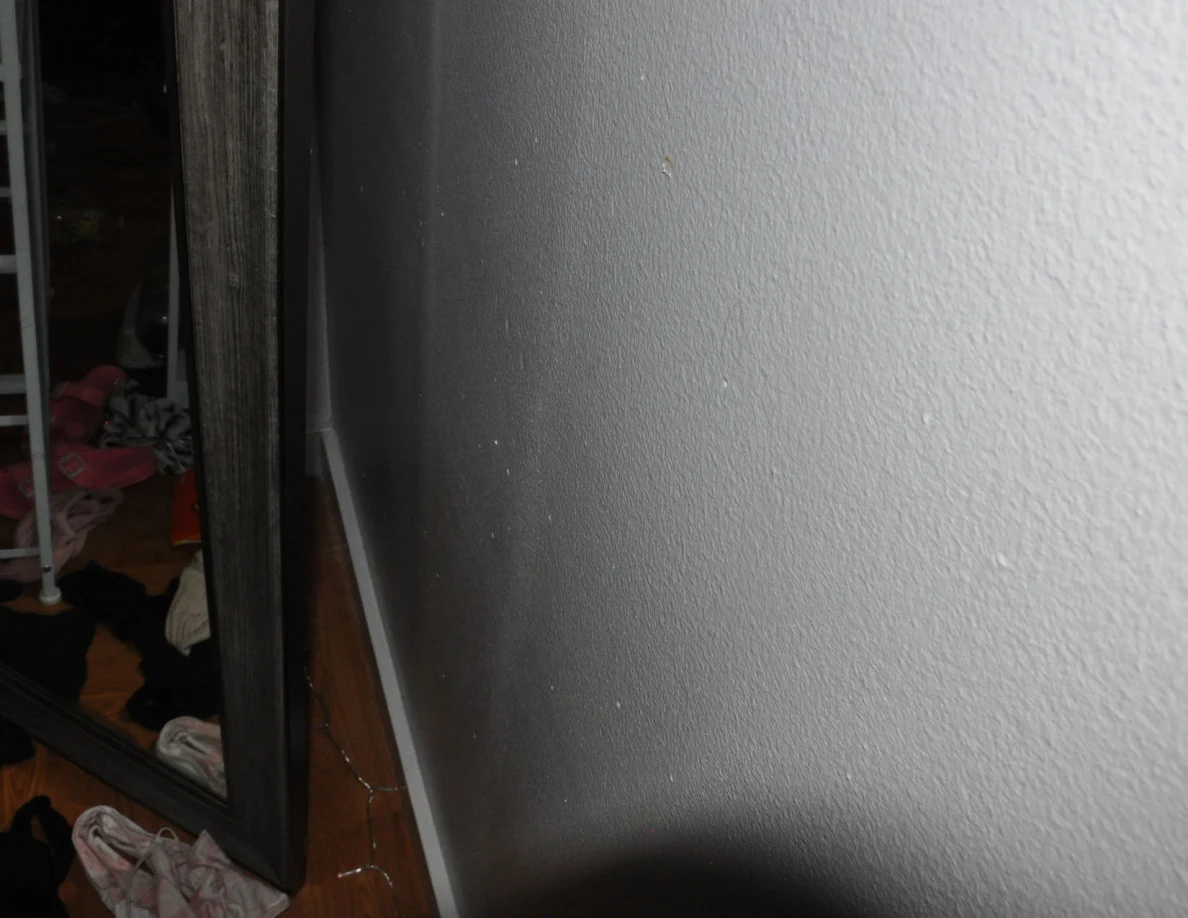 Close view of a pale wall beside a wood-look mirror frame.