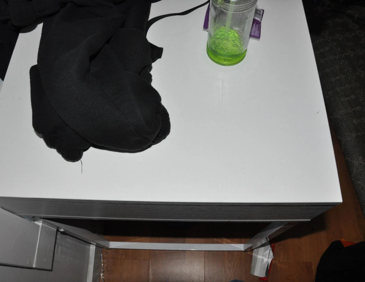 Dark clothing and a green liquid pump bottle on a white desk.