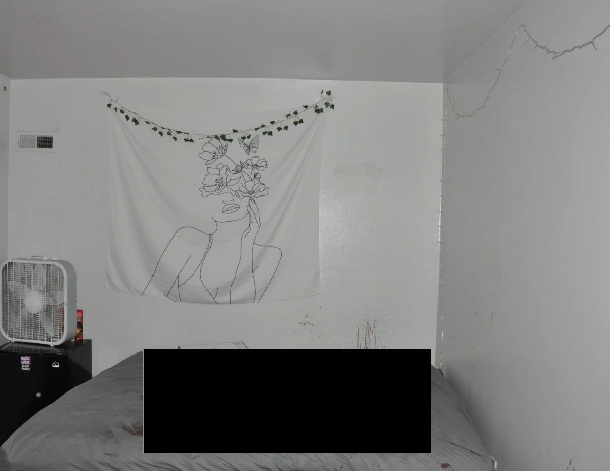 Floral line-art wall hanging above a partly redacted bed beside a box fan.