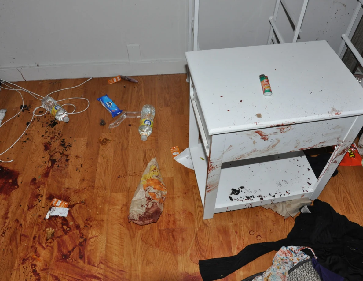White bedside cabinet with reddish marks beside bottles and marked flooring.