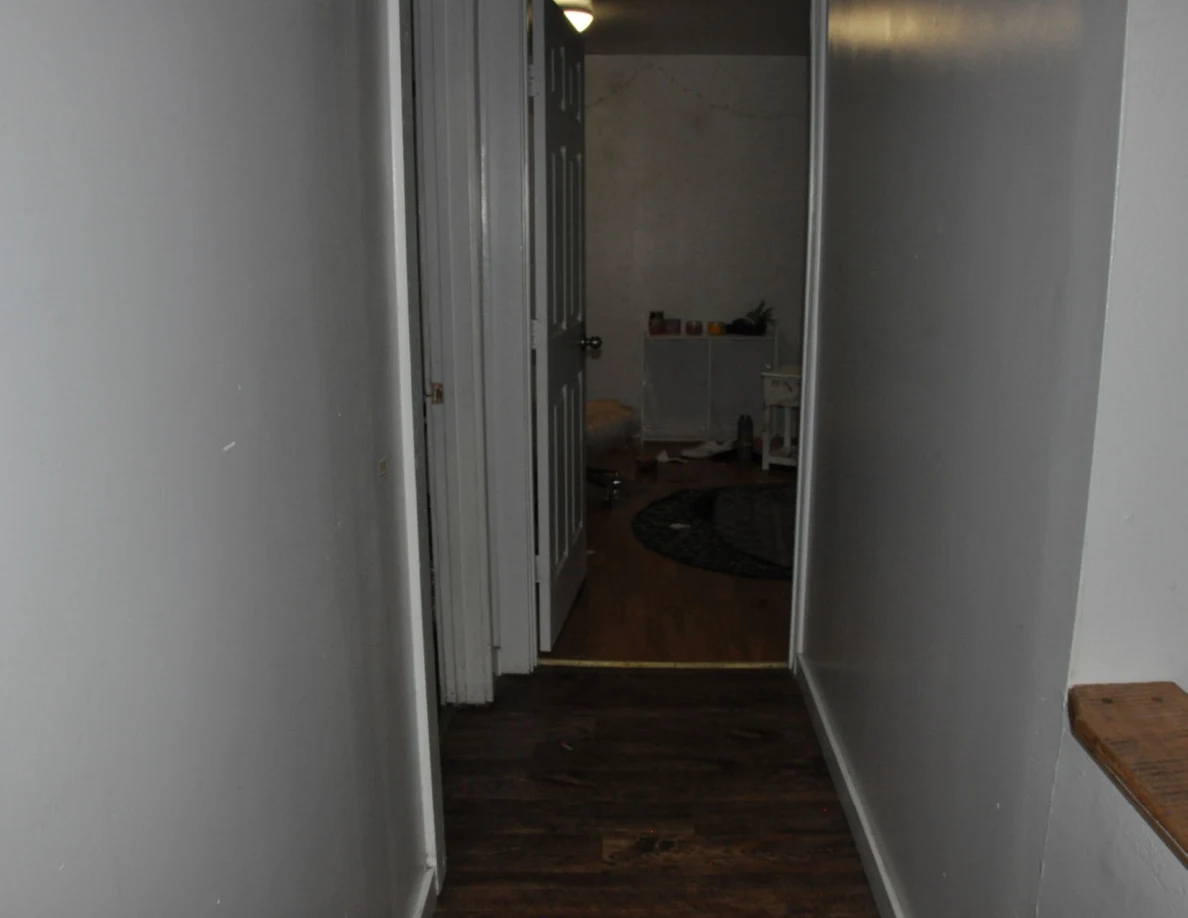 Dim hallway looking toward an open bedroom.