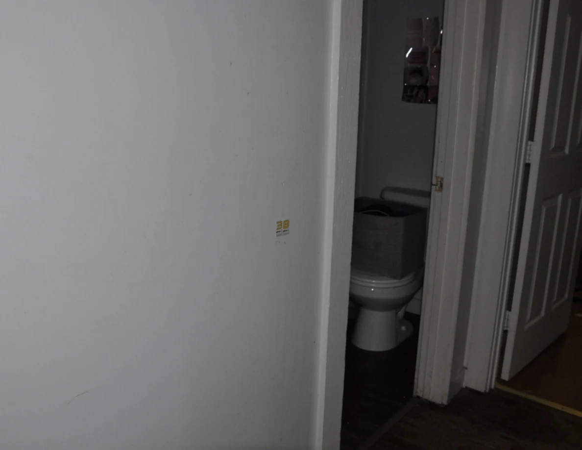 White hallway wall beside an open bathroom with a visible toilet.