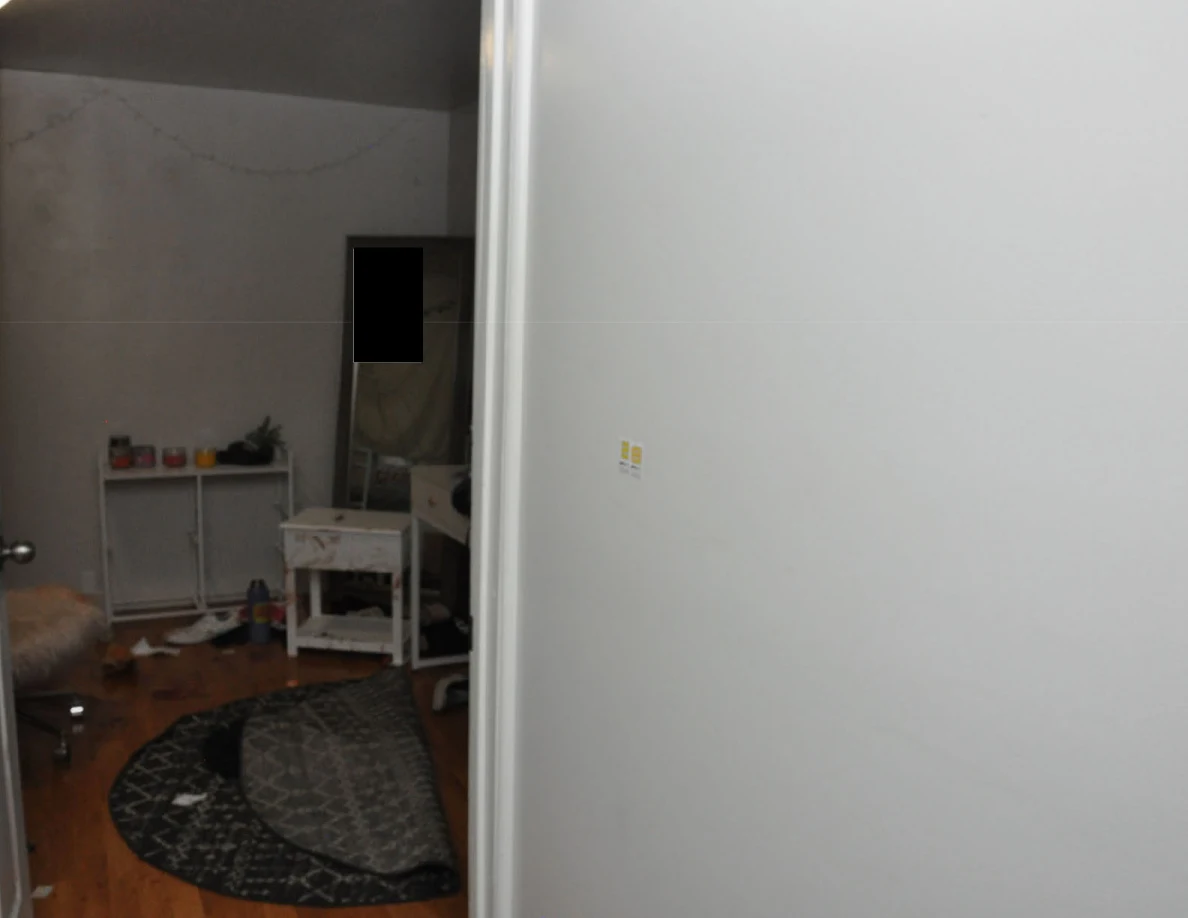 Bedroom doorway with folded rug and white furniture beside small wall markers.