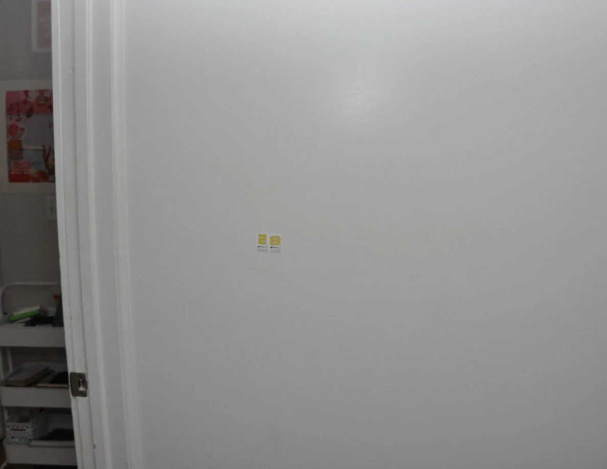 Small yellow scale stickers on a white wall beside a bedroom doorway.