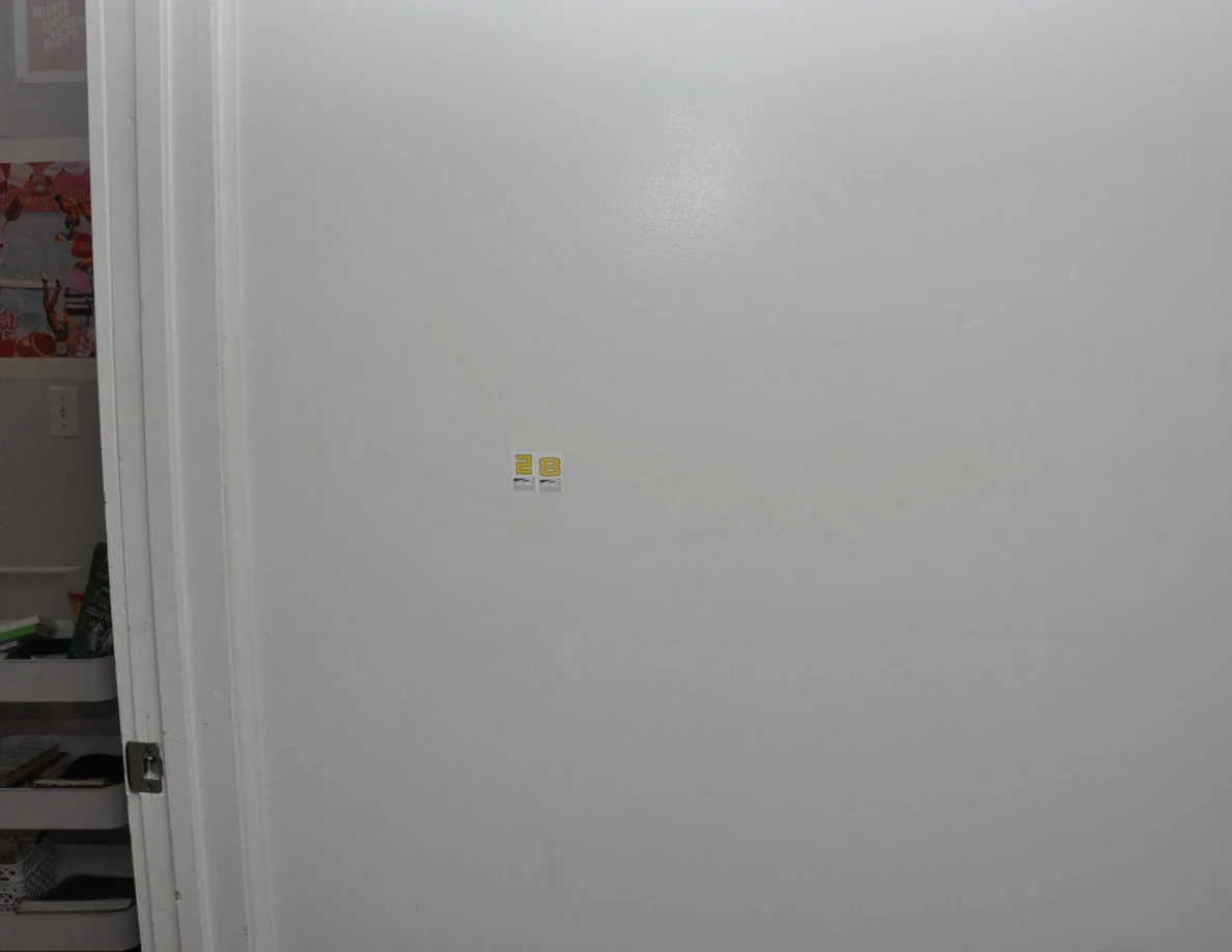 Closer view of small yellow scale stickers on a white wall.
