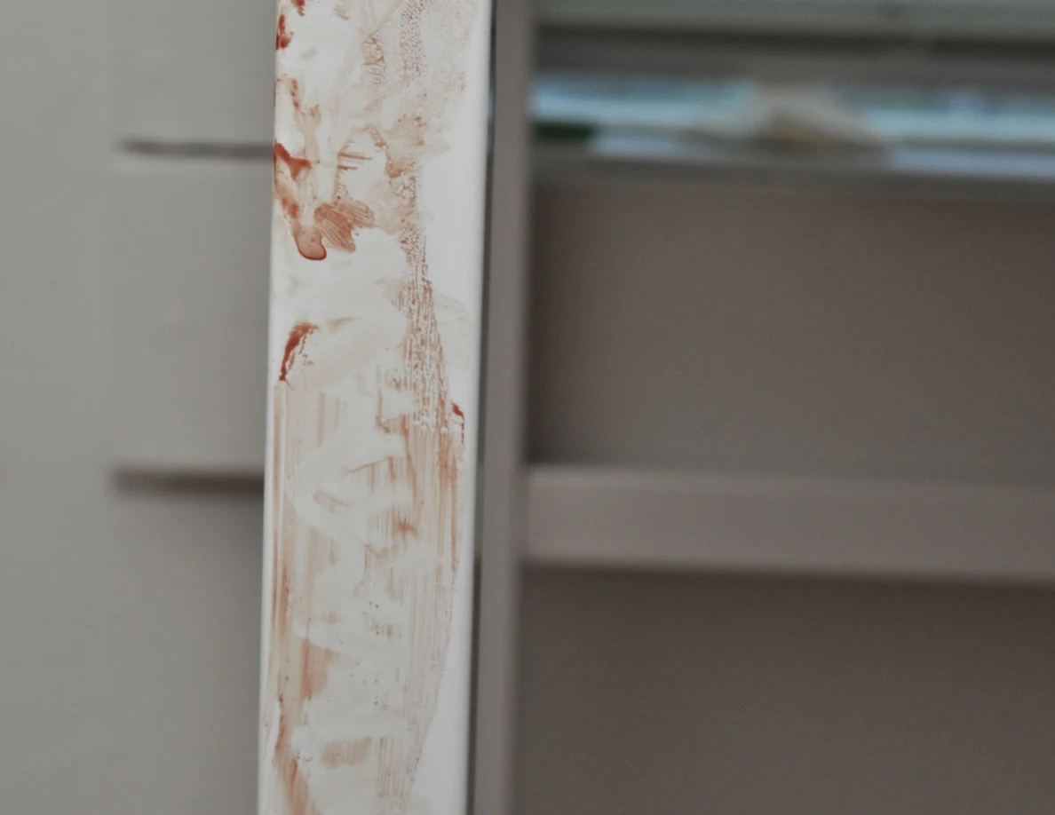 Lower section of a white desk leg with reddish smears.