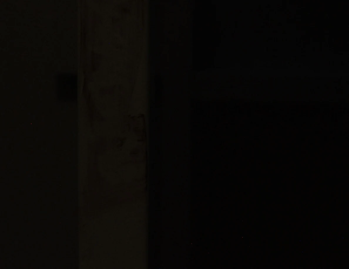 Very dim close view of a vertical furniture edge with faint marks.