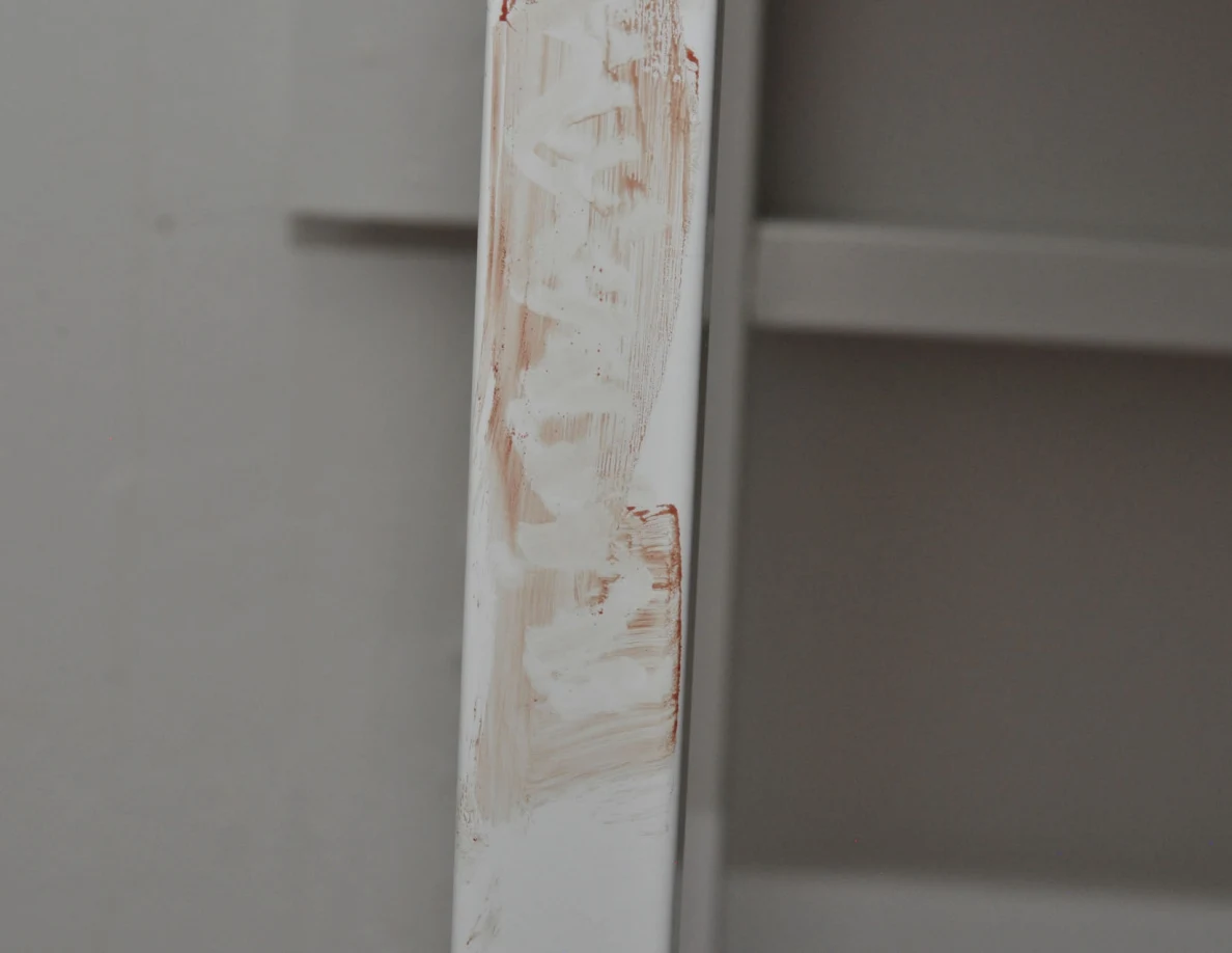 Reddish streaks along a white desk leg.